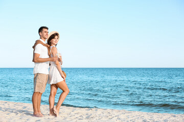 Happy young couple drinking champagne on sea beach