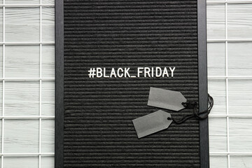 Board with text BLACK FRIDAY and tags on wooden background