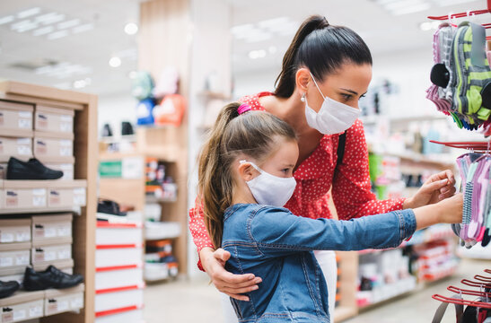 Mother and daughter with face mask shopping in shoeshop, coronavirus concept.