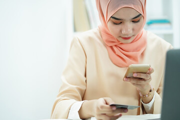 Muslim woman use a credit card and smartphone for online shopping and online payment via internet. Technology concept.