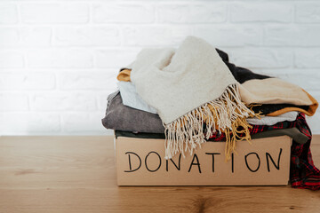 Cardboard donation box full with used clothes. Concept of charity, donation and clothes recycling....
