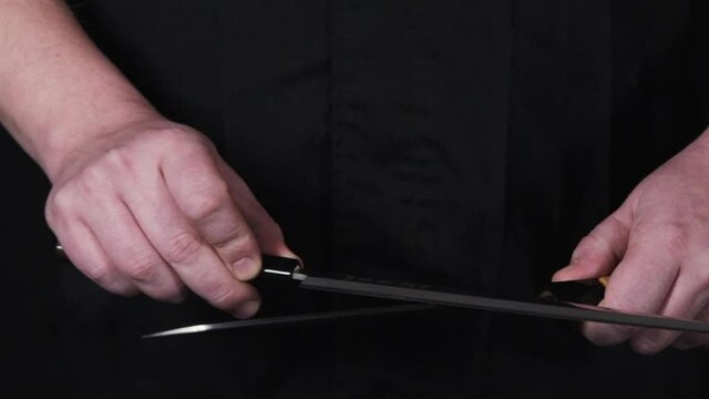 Someone sharpening knives in slow motion. Chef sharpening knife. Hands and knife. Japanese knifes.
