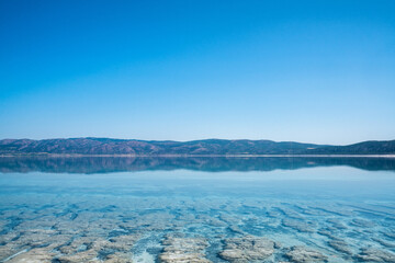 Fototapeta na wymiar The bottom and surface with crystal clean water of Salda Lake in Turkey. Travel Tourism concept.