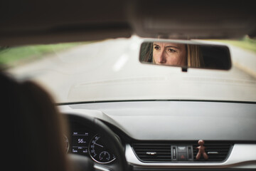 Fototapeta premium Pretty midle aged woman at the steering wheel of her car commuting to work