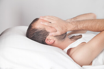 Fototapeta na wymiar Caucasian depressed man lying in his bed and covering face.