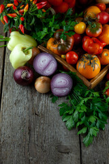 Tomatoes, peppers, onions on the table. Top view. Vegetable food. Still life. Tomato of different varieties. Preservation of the autumn harvest of vegetables. Wooden background. Copy space.