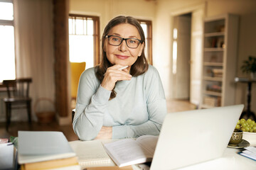 Age, technology and occupation. Successful female journalist working on retirement sitting at table...