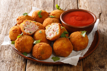 Popular fried hot appetizer sauerkraut balls stuffed with ham served with ketchup close-up in a plate on the table. horizontal