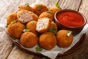 Crispy sauerkraut balls stuffed with ham served with ketchup close-up in a plate on the table. horizontal