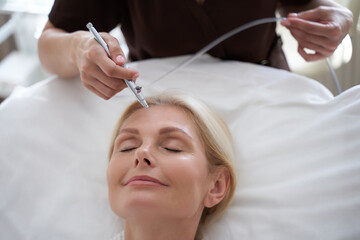Obraz na płótnie Canvas Cosmetologist using a modern device for facial procedures