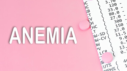 Word ANEMIA on pink background, medical concept, top view