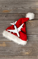 Obraz na płótnie Canvas Red Santa hat with toy plane on old wooden background