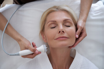 Naklejka premium Smiling lady ejoying anti-aging treatments in beauty clinic