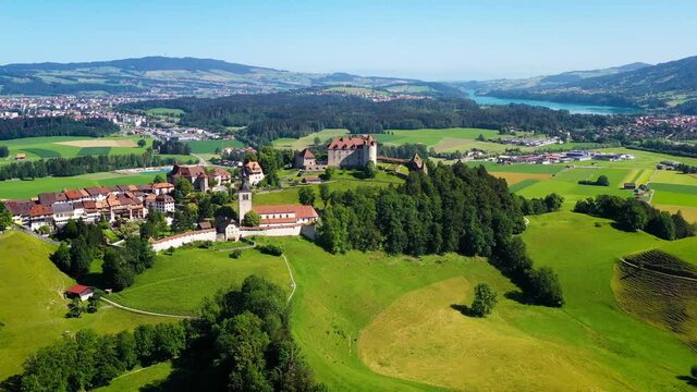Beautiful Gruyeres Castle in Switzerland, under the blue sky. Aerial view with a drone of the beautiful castle in with lush green hills and agricultural fields all around - 4K