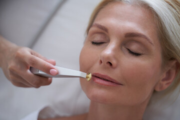 Cosmetologist using a device to improve the skin near the lips