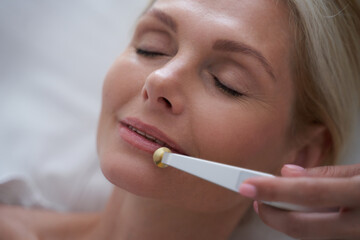 Blonde lady with closed eyes during cosmetic procedures