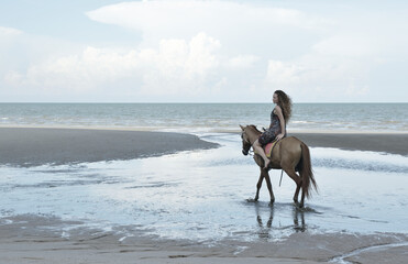 Woman riding horse on the beach over sea and sky, soft tone, Summer holiday and travel concept