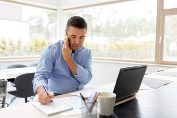 technology, remote job and business concept - middle-aged man calling on smartphone and writing to notebook at home office
