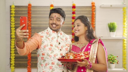 Indian couple in traditional dress taking selfies after celebrating Karva Chauth festival at home - Concept of using Mobile, technology during festival celebrations