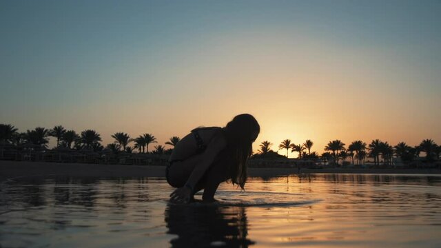 Beautiful young woman relaxing in water at early morning resort beach.