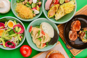 Variety of food dishes on bright green background. Table covere with food flat lay, top view, frame.