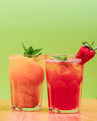 Summer drinks with fruit juice and ice. Refreshing summer beverages in different glasses over green background.
