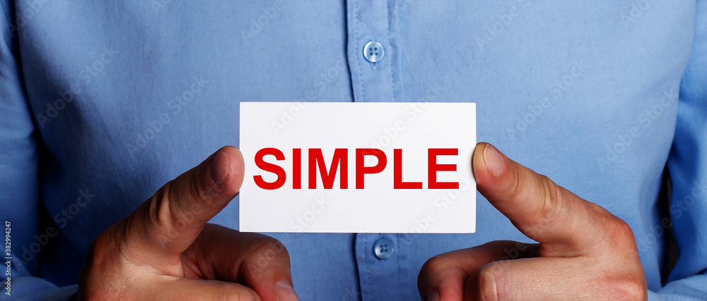 Poster a man holds with his index fingers a white card with the text simple