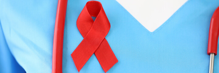 Doctor has red ribbon on his chest. Examination and prevention of breast diseases concept