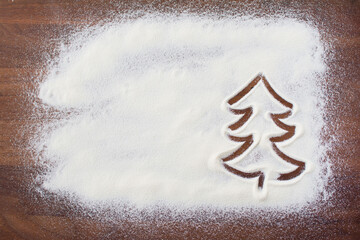 Christmas tree sketch on flour background. Flour spread on the wooden table. White flour looks like snow. Top view flat lay Merry christmas. Copy space.
