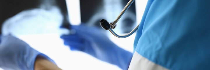 Doctor with stethoscope and in gloves holds xrays closeup. X-rays of skeleton concept