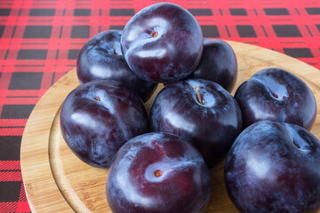 A ripe, juicy blue plum lies on a wooden kitchen board.