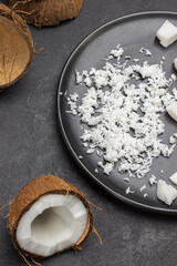 Coconut flakes on black ceramic plate. Coconut shells