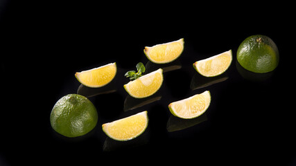 Slices and slices of lime lemon on a black background close up