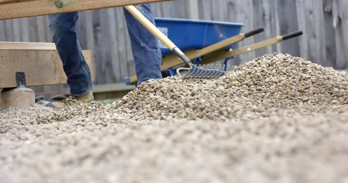 Man leveling riverstone for yard work - close up on flat rake - slow motion