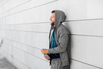 fitness, sport and people concept - happy smiling young man with bottle of water outdoors