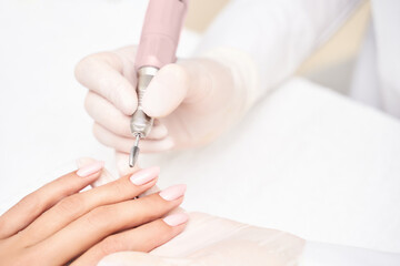 Obraz na płótnie Canvas Beautiful salon procedure with pink manicure on towel background. For decoration design. Machine healthcare. Woman body care. Spa treatment. White background. Nail brush and polish.