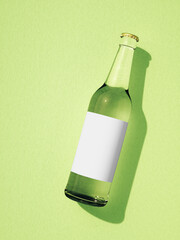 One closed transparent glass beer bottle laying on light green surface.