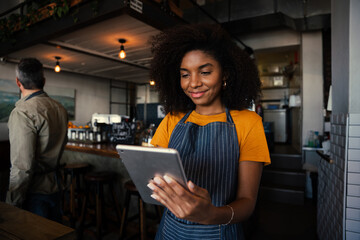 Smiling waitress choosing meal option for customer scrolling on digital tablet in trendy cafe 