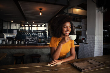 Mixed race female customer enjoying hot coffee sitting in rustic restaurant 