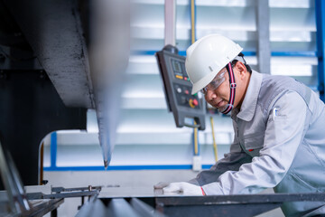 Asian technician worker wearing a safety suit and sheet Metal Bending in industrial factory, Safety first concept.