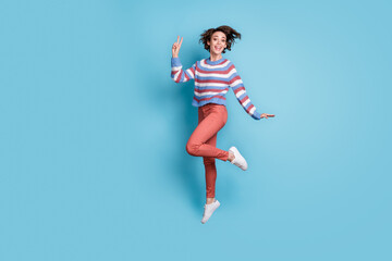 Fototapeta na wymiar Full length body size photo of jumping up female student showing gesture v-sign two fingers isolated on vibrant blue color background