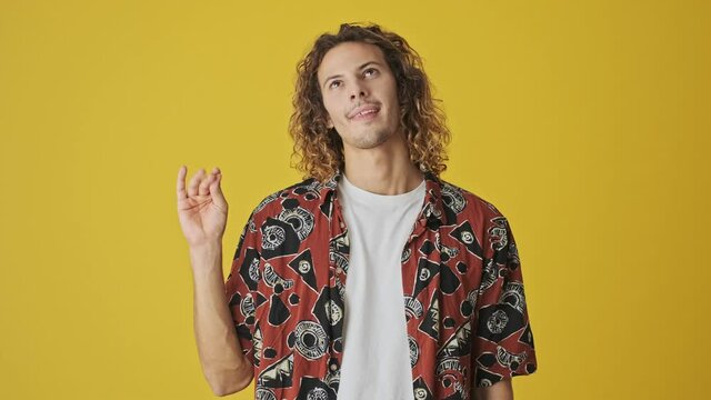 An attractive young man is doing blablabla gesture standing isolated over yellow background