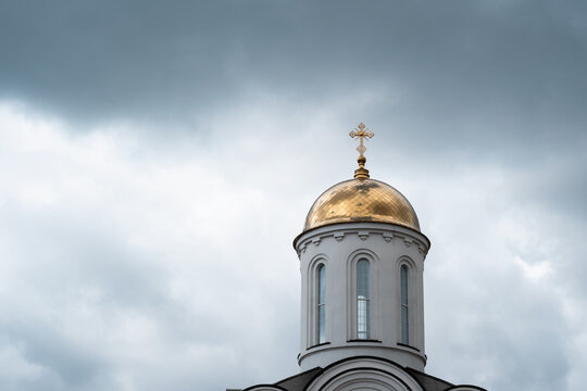 White church with golden dome and cross close up