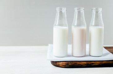 dairy products milk and yogurt in identical small transparent bottles on a white wooden table on a gray light background with free space
