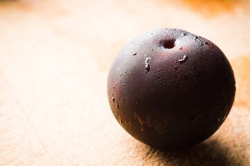Freshly harvested red plum with condensation at cold autumn morning. Selective focus. Shallow depth of field.