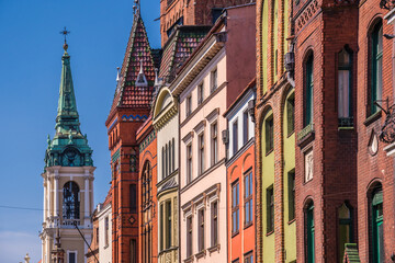 Fototapeta na wymiar Church of the Holy Spirit surrounded by buildings under the sunlight and a blue sky in Torun, Poland