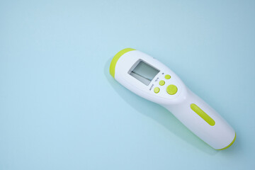 Digital medical infrared forehead thermometer gun non contact for measuring temperature, for COVID testing on blue background. Copy space.