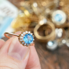 hand takes ring with big topaz stone and many diamonds, jewelry scrap of gold and silver and money,...