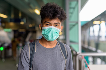 Face of young Asian tourist man as backpacker with mask at the sky train station