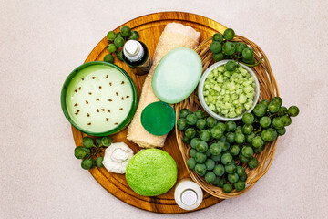 Natural spa accessories and green grapes placed on a wooden plate